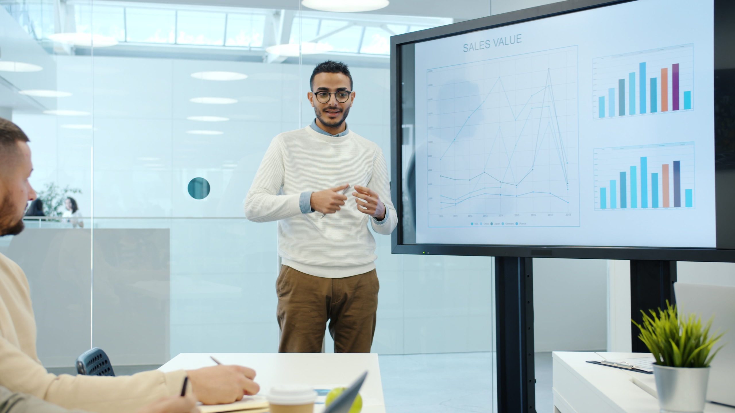Professional delivering a business presentation with charts in a modern office setting.